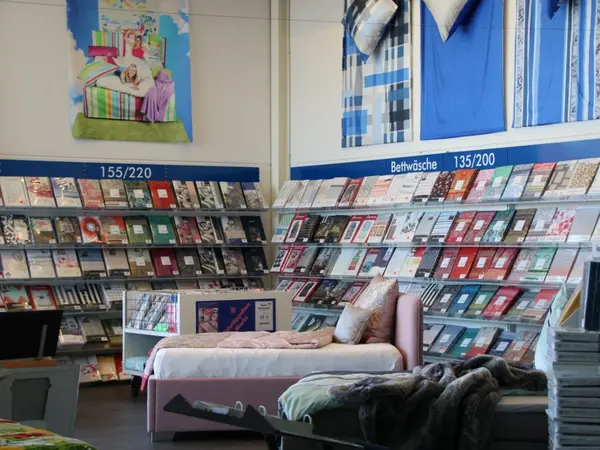 Bettwäsche-Abteilung im Fachgeschäft mit Regalen und Bett im Showroom