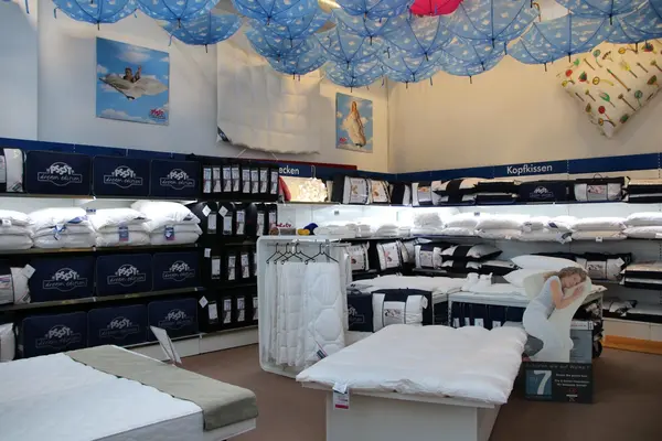 Bettengeschäft mit Kissen, Decken und Matratzen, dekoriert mit blauen Wolken-Schirmen.