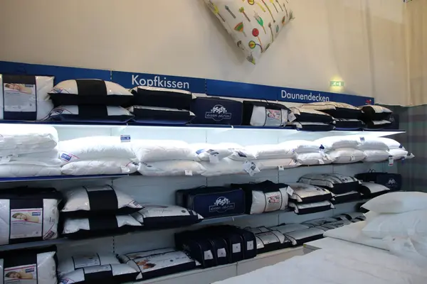 Regal mit verschiedenen Kopfkissen und Daunendecken im Bettwaren-Fachgeschäft.