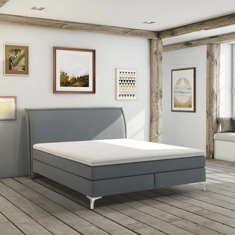 Modernes Schlafzimmer mit Boxspringbett, Holzbalken, Wandbildern und viel Tageslicht.